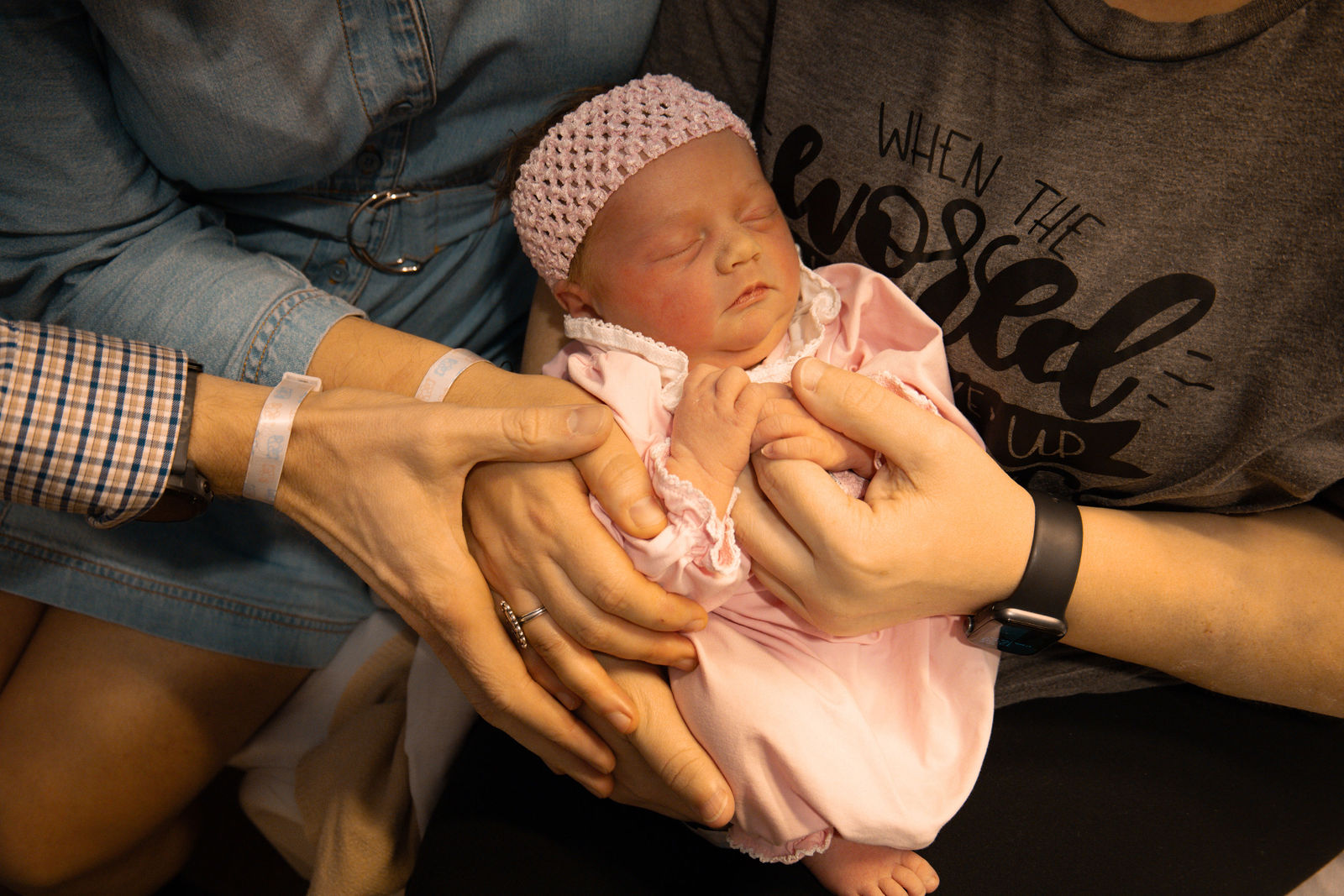 Newborn held by parents and surrogate